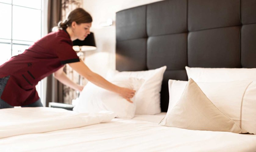 Blick in ein Hotelzimmer im Schindelbruch, wo das Bett frisch bezogen wird